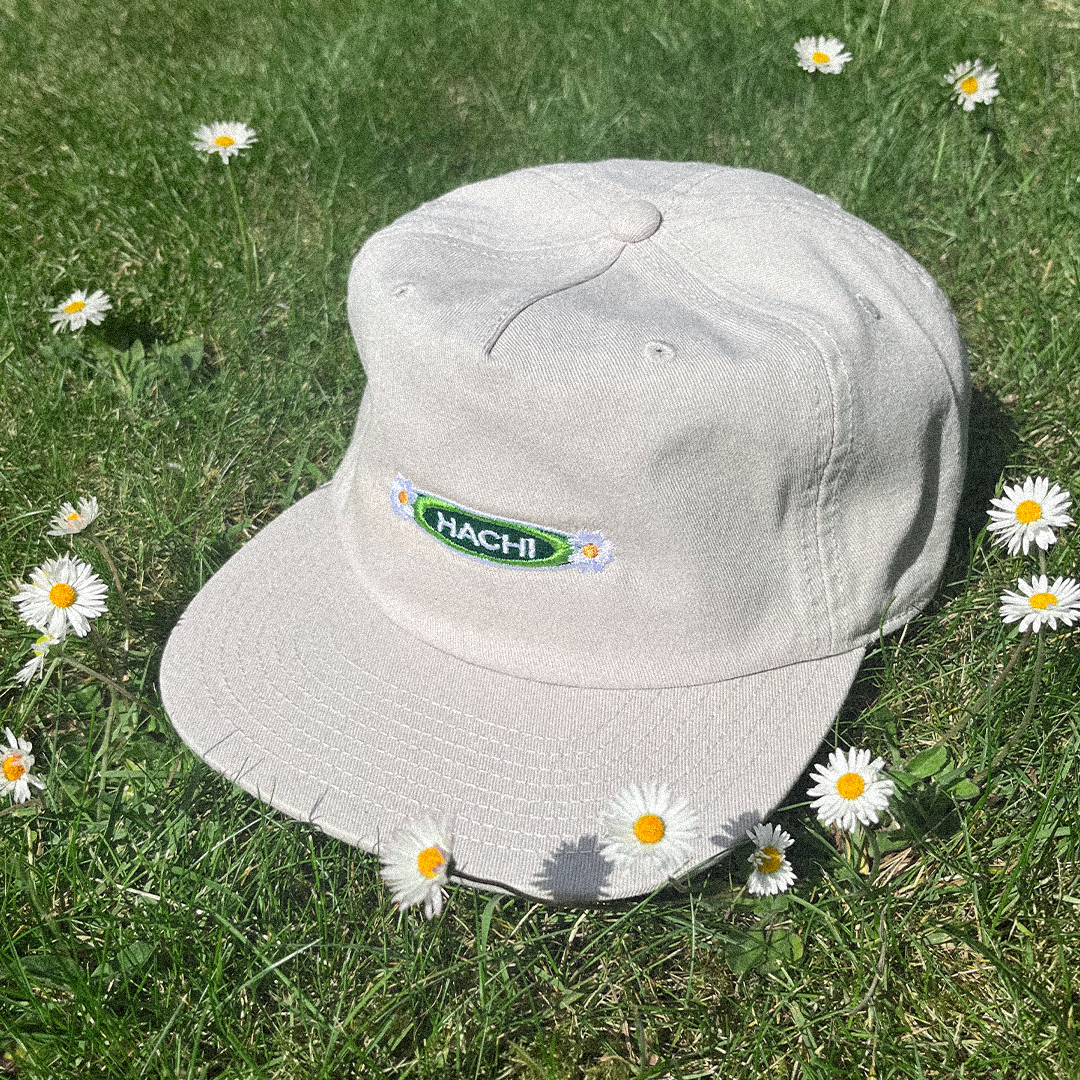 Hanami cap with embroidered logo on grass with daisies